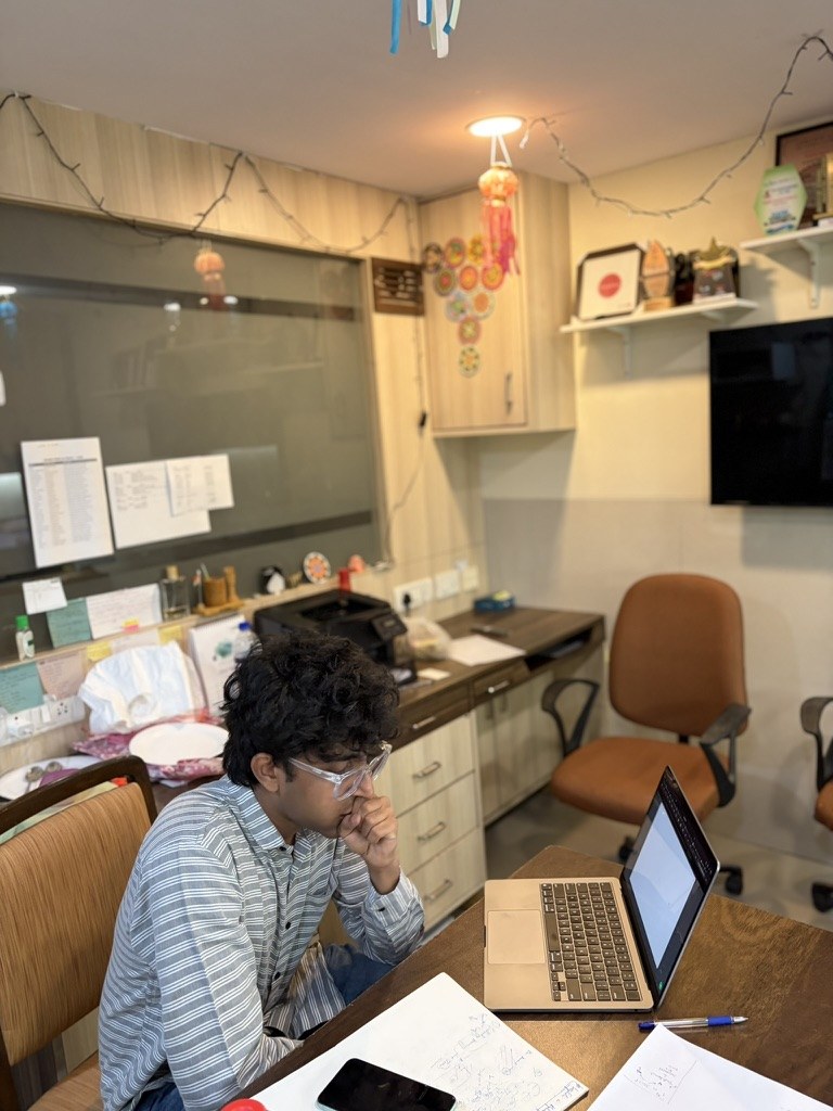 Kavish working at his desk with a laptop and notes