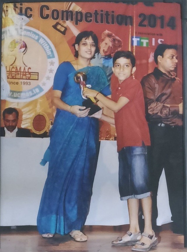 Kavish as a child receiving a trophy on stage at an arithmetic competition in 2014